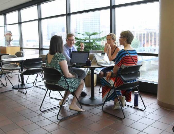 A group of teachers sit around a table talking during Summer Institute
